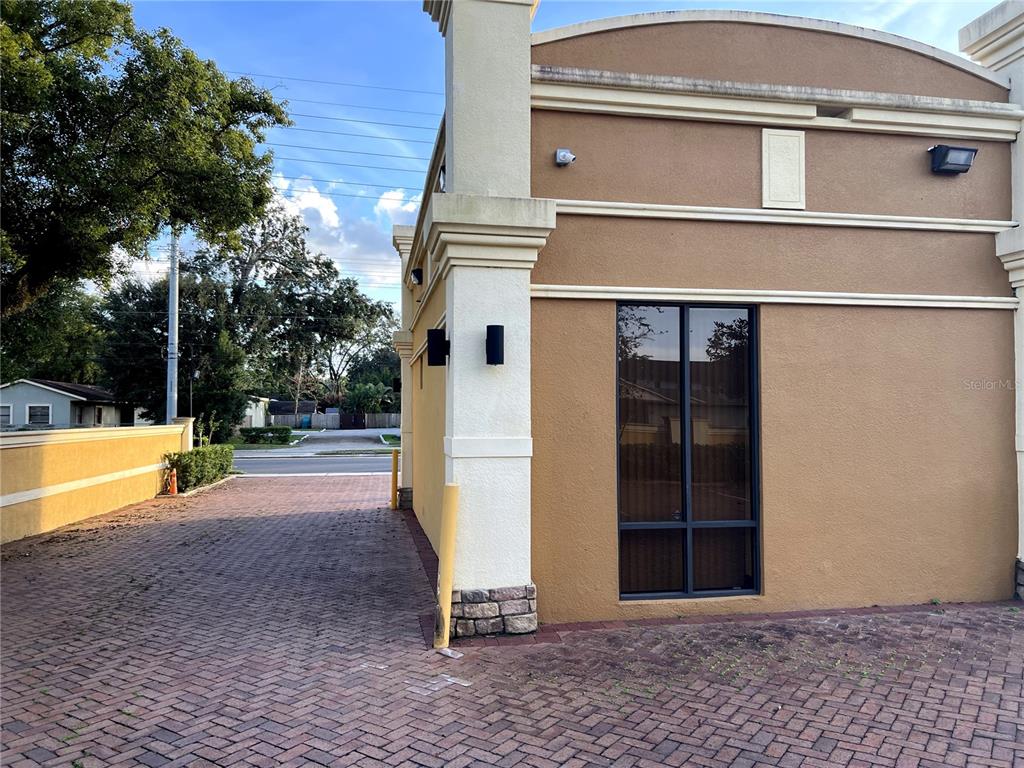 The exterior of a tan commercial building features a brick-paved driveway and a tall window — 1313 E MICHIGAN STREET, ORLANDO, FL