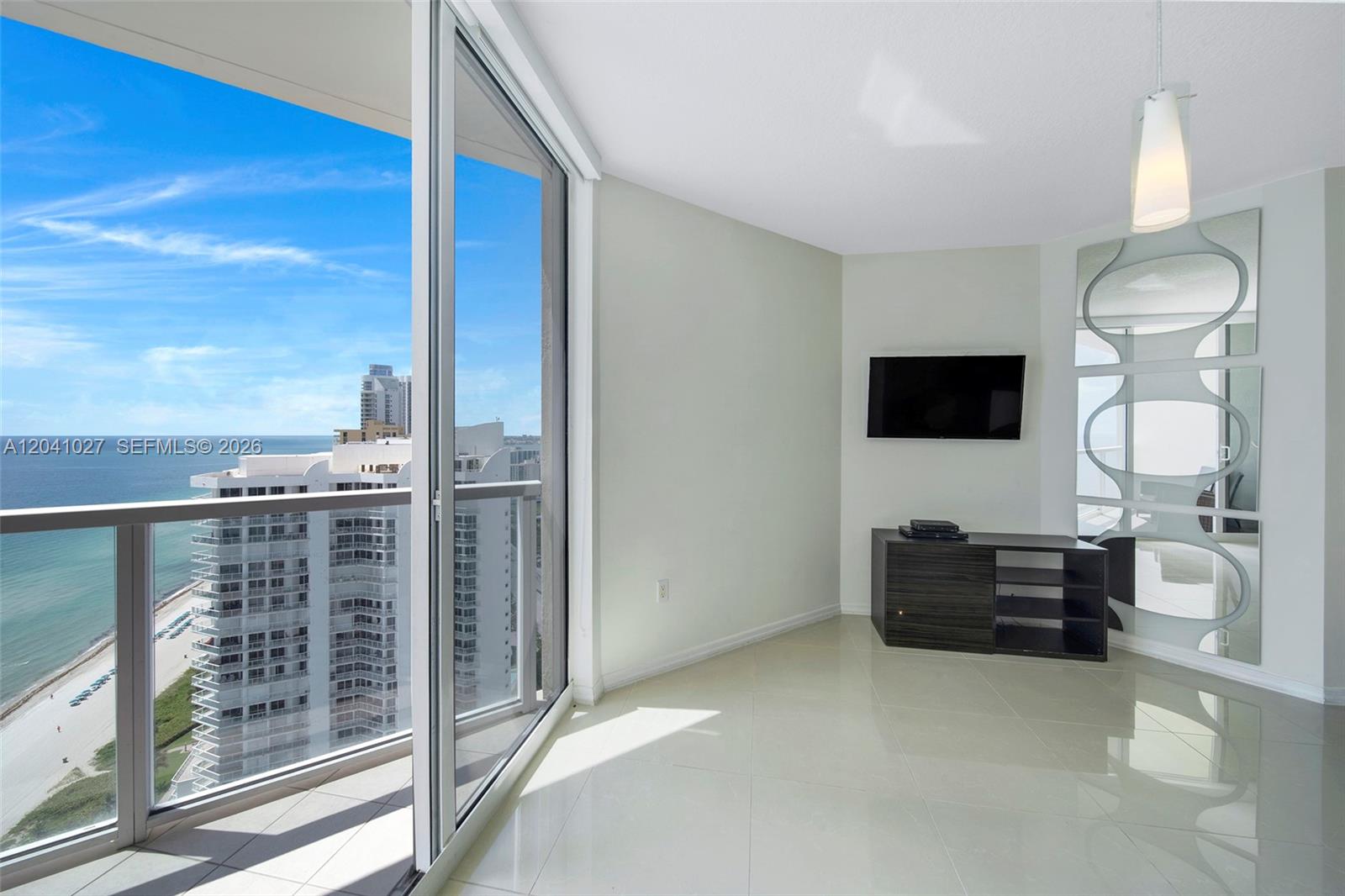 A living room features light tile floors, a wall-mounted television, and a balcony overlooking the ocean — 16699 Collins Ave # 3309, Sunny Isles Beach FL 33160, SUNNY ISLES BEACH, FL