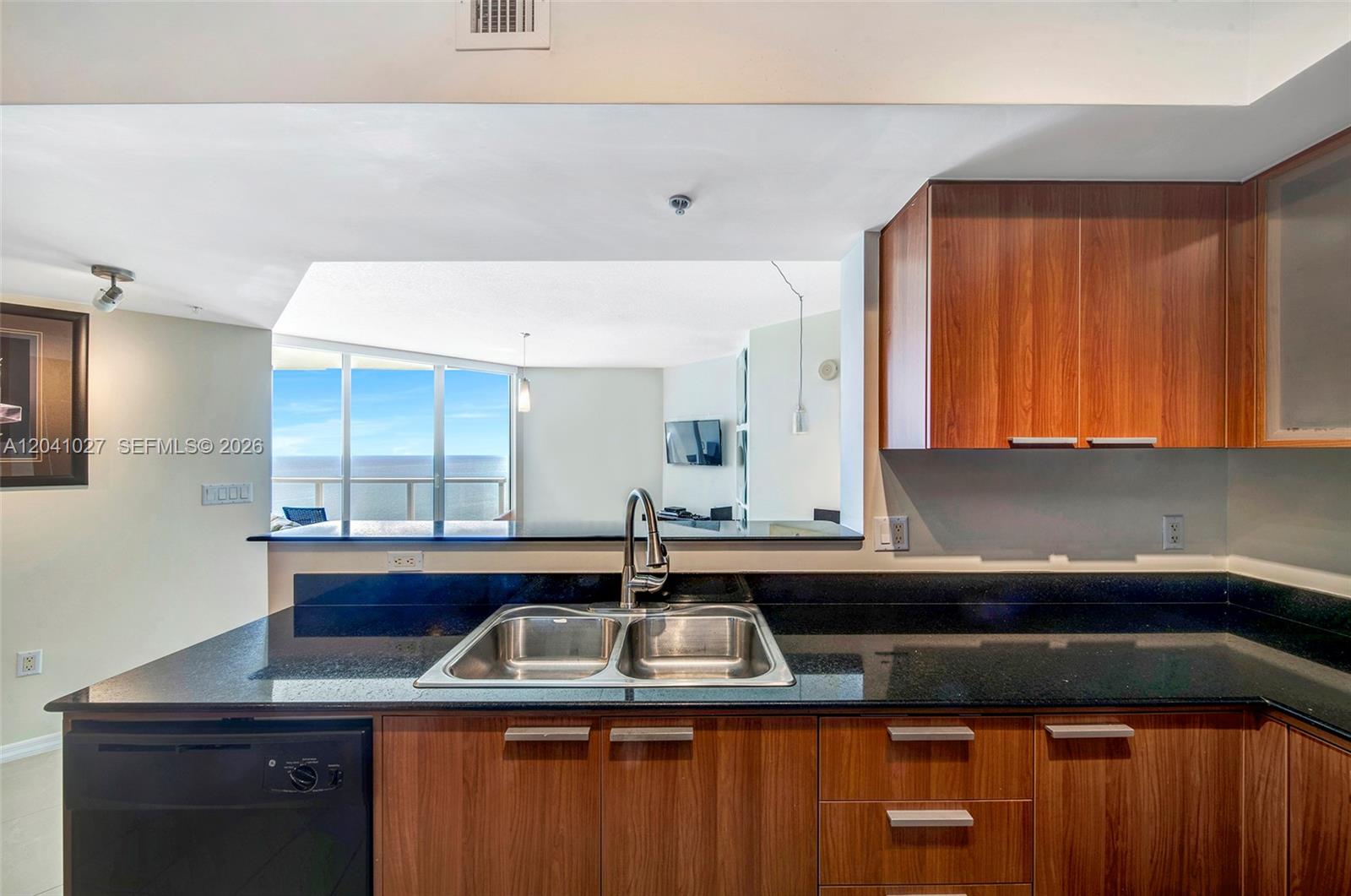 A kitchen features wood cabinets, black granite countertops, a double sink, and ocean views — 16699 Collins Ave # 3309, Sunny Isles Beach FL 33160, SUNNY ISLES BEACH, FL