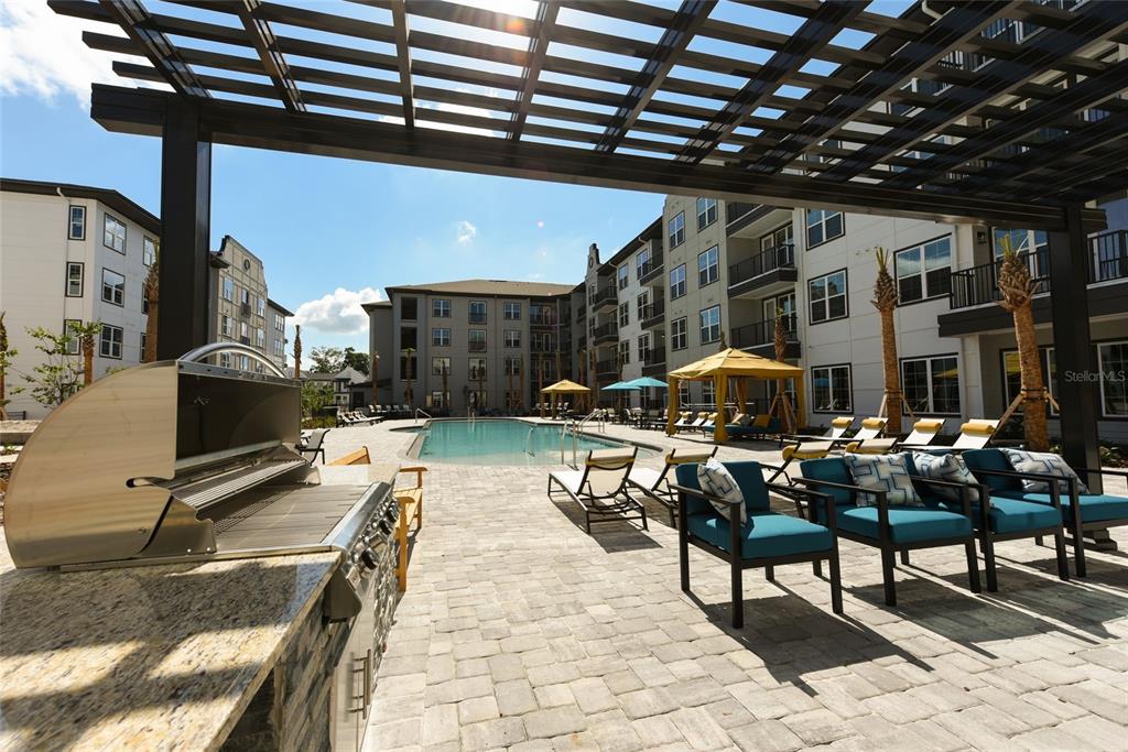 An outdoor patio area features a stainless steel grill, lounge seating, and a swimming pool — 6629 DAN DICIOLLA DRIVE UNIT B2, WILDWOOD, FL