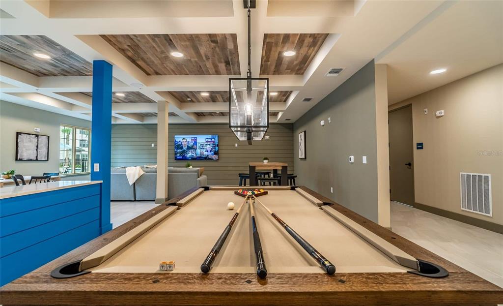 A game room features a pool table, wood-paneled ceiling, and a television mounted on a wall — 6629 DAN DICIOLLA DRIVE UNIT B2, WILDWOOD, FL