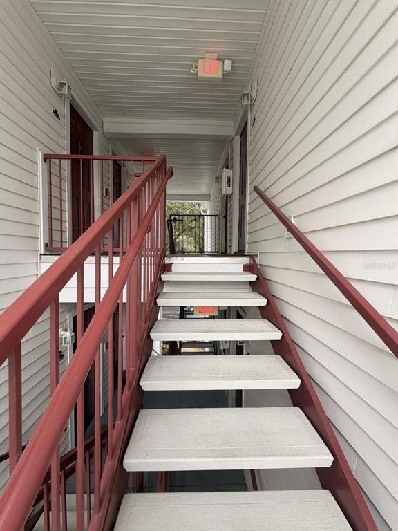 An exterior staircase with red metal railings leads to an upper-level apartment walkway — 11568 WESTWOOD BOULEVARD UNIT 1034, ORLANDO, FL