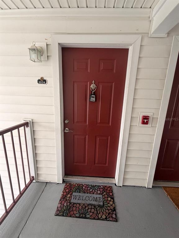 A red front door with a lockbox and a welcome mat on a concrete porch — 11568 WESTWOOD BOULEVARD UNIT 1034, ORLANDO, FL