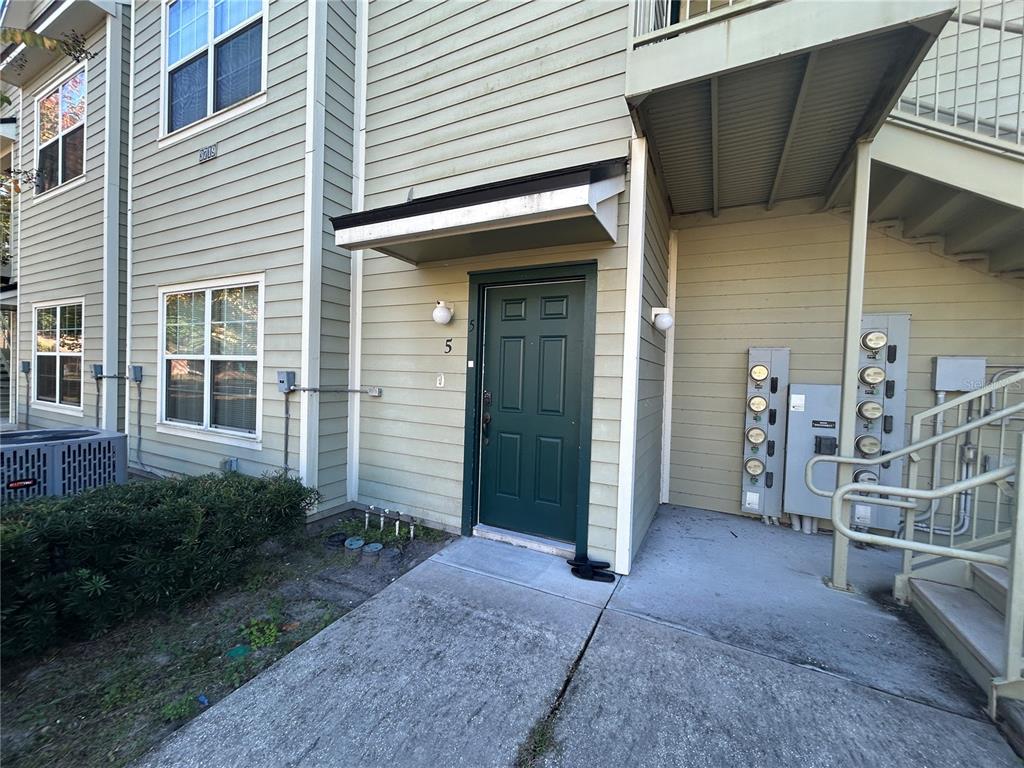 An exterior view of a ground-level apartment entrance with light green siding and a dark door — 3719 S LAKE ORLANDO PARKWAY UNIT 05, ORLANDO, FL