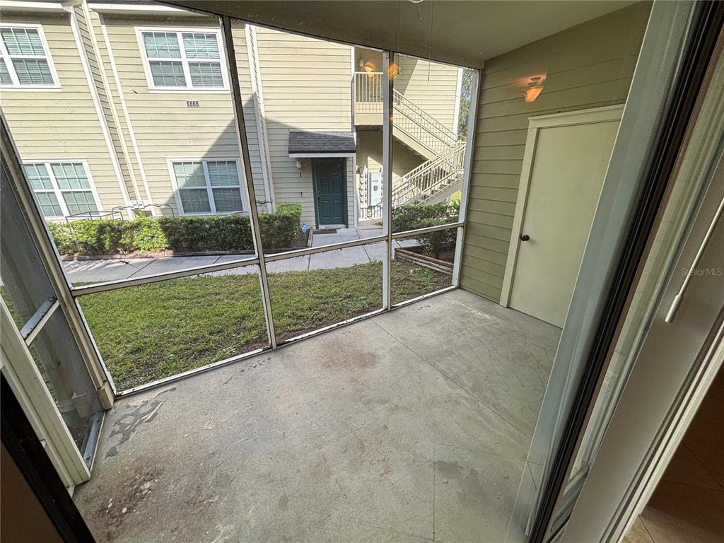 A screened-in patio features a concrete floor, a storage closet, and a view of neighboring apartments — 3719 S LAKE ORLANDO PARKWAY UNIT 05, ORLANDO, FL