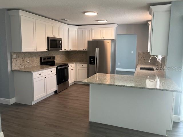 A kitchen features white cabinets, granite countertops, stainless steel appliances, and wood-look flooring — 5241 MAGNOLIA TERRACE, FRUITLAND PARK, FL