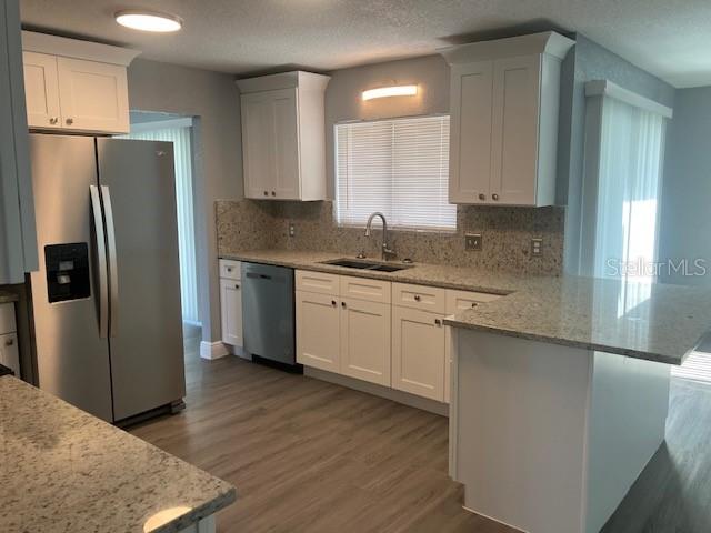 A kitchen features white cabinets, granite countertops, stainless steel appliances, and light wood-look flooring — 5241 MAGNOLIA TERRACE, FRUITLAND PARK, FL