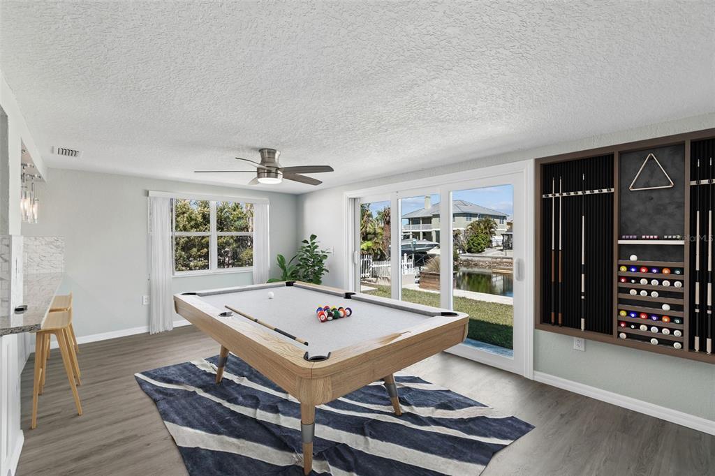 A game room features a pool table, a wall-mounted cue rack, and sliding glass doors — 4417 RUDDER WAY, NEW PORT RICHEY, FL