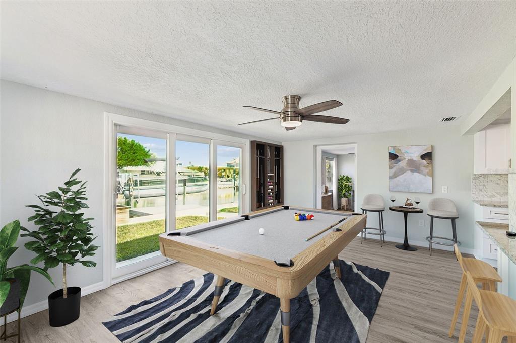 A game room features a pool table, a ceiling fan, and sliding doors overlooking a canal — 4417 RUDDER WAY, NEW PORT RICHEY, FL