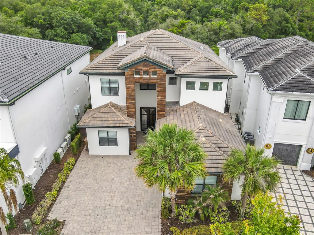 An aerial view shows a two-story house with a tiled roof and a paved driveway — 8193 VALHALLA TERRACE, REUNION, FL