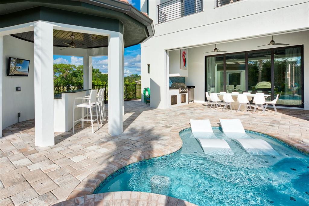 A patio features a covered bar, an outdoor kitchen, and a pool with lounge chairs — 8193 VALHALLA TERRACE, REUNION, FL