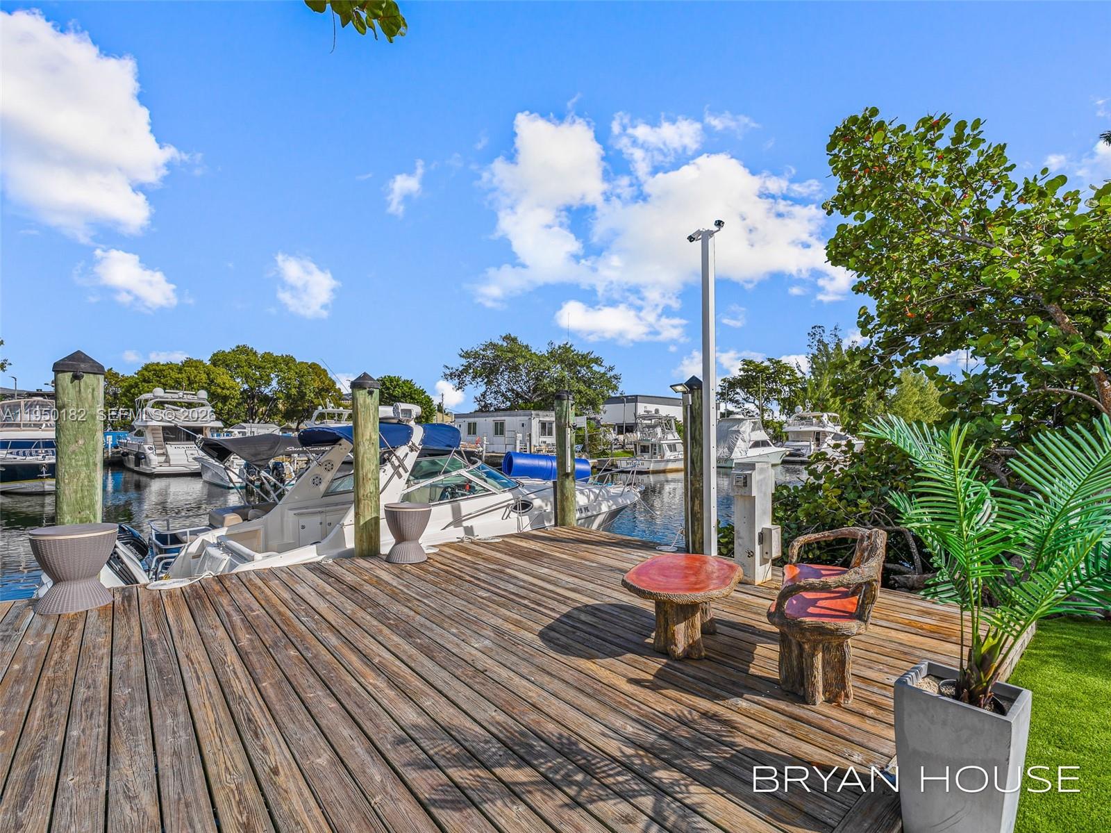 A wooden deck features a small table and chair set overlooking a boat-filled marina — 3341 NW 20th St, Miami FL 33142, MIAMI, FL