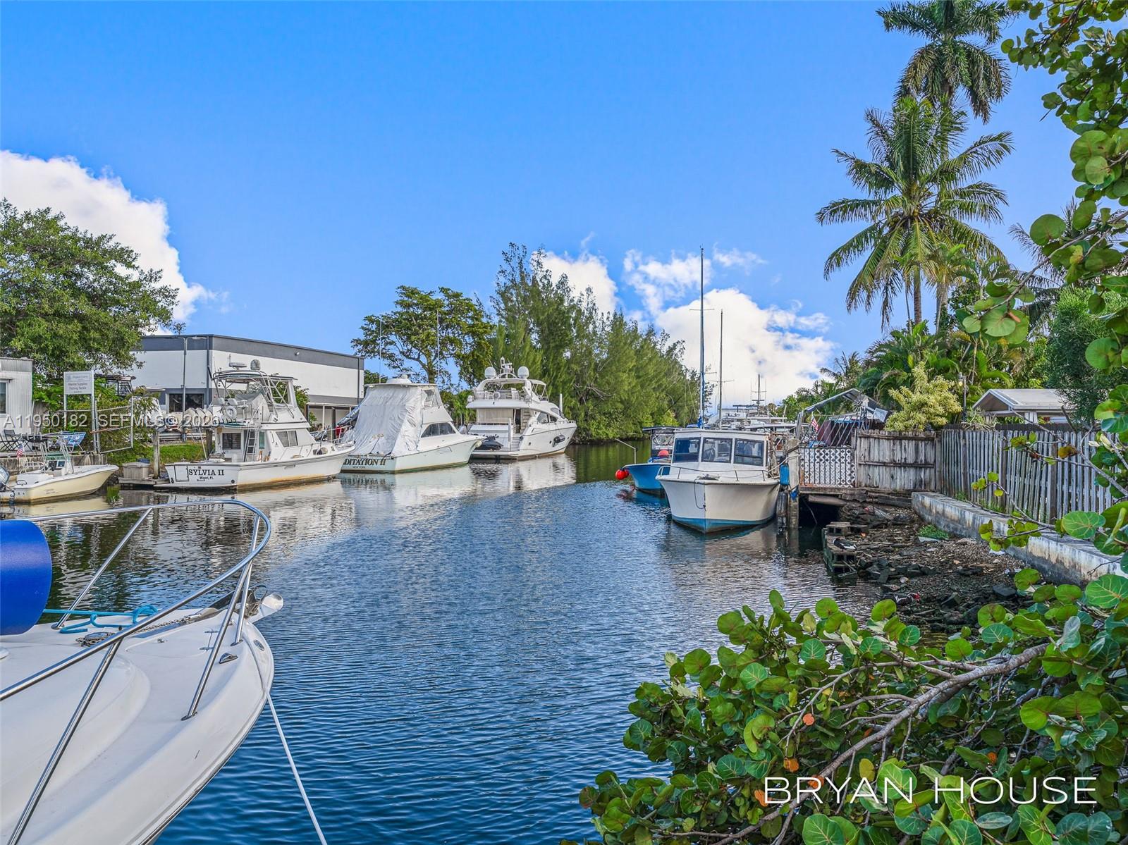 Several boats are docked along a narrow canal lined with trees and a wooden fence — 3341 NW 20th St, Miami FL 33142, MIAMI, FL