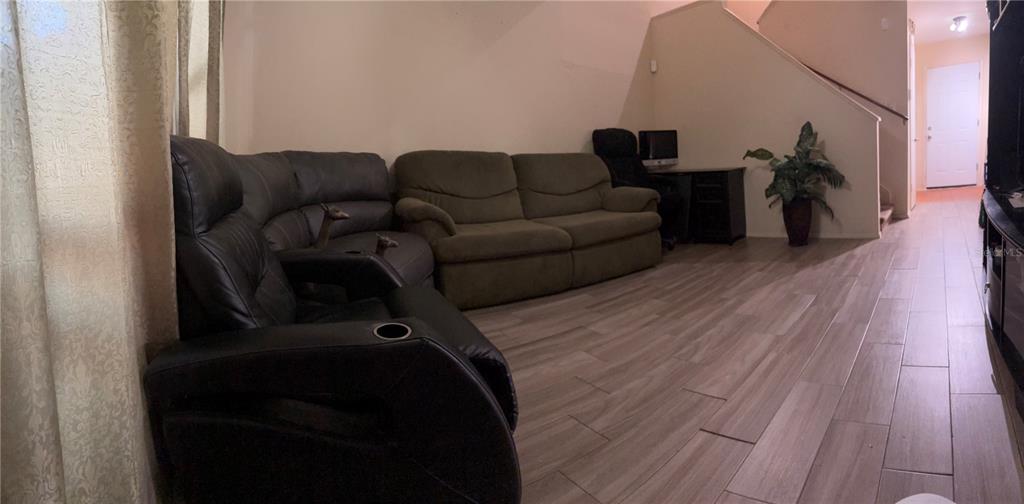 A living room features a black leather recliner, a green sofa, and wood-look tile flooring — 1830 WARRINGWOOD DRIVE UNIT B3, ORLANDO, FL