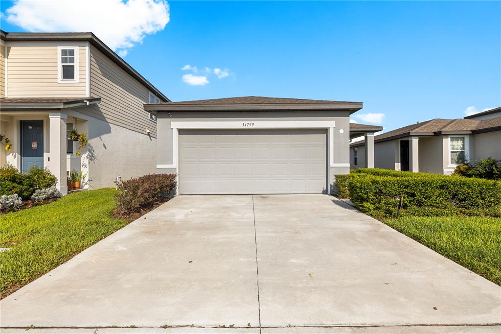 A concrete driveway leads to a two-car garage on the front of a suburban house — 34799 TELLURIDE LANE, ZEPHYRHILLS, FL