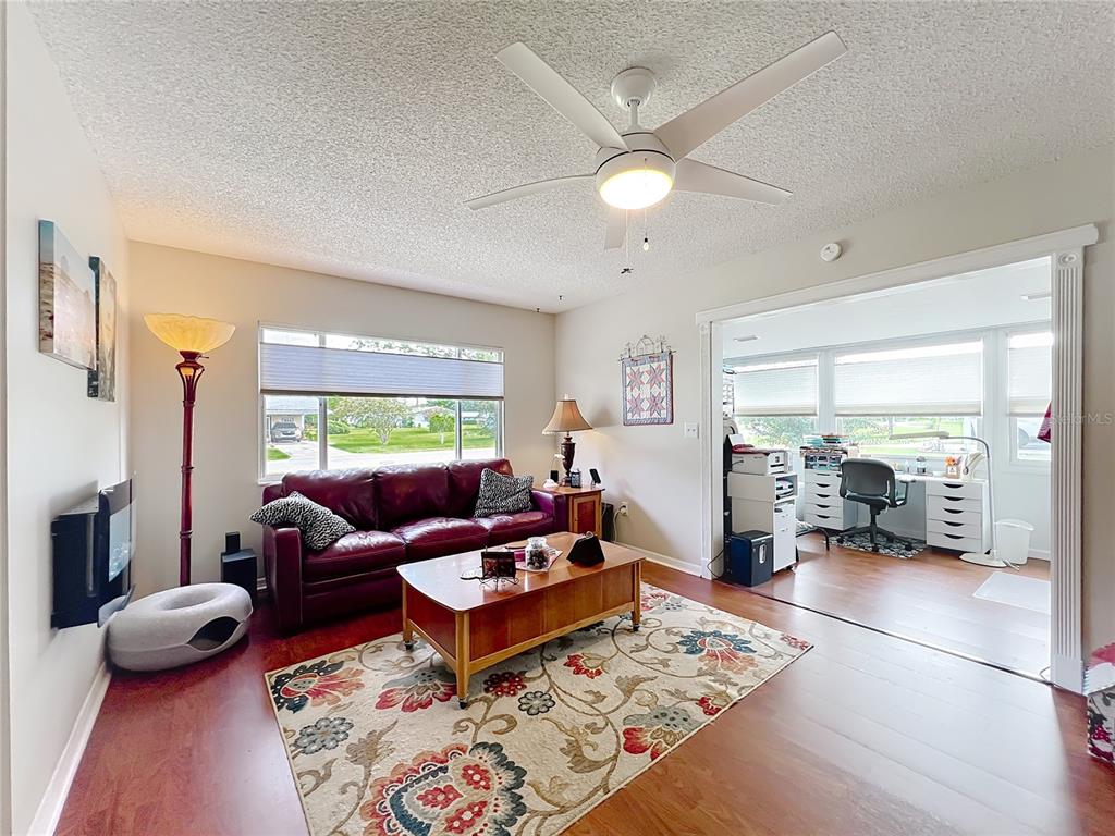 A living room with a red leather sofa, floral area rug, and an adjacent office space — 6468 SW 107TH PLACE, OCALA, FL