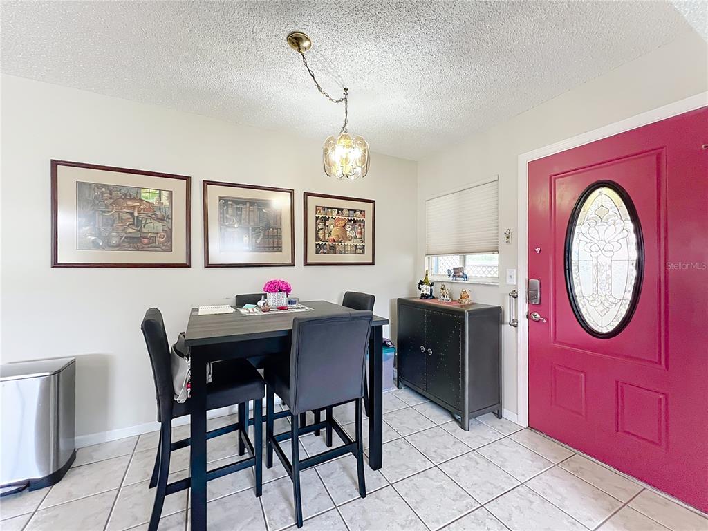 A dining area features a dark table, four chairs, and a bright pink front door — 6468 SW 107TH PLACE, OCALA, FL