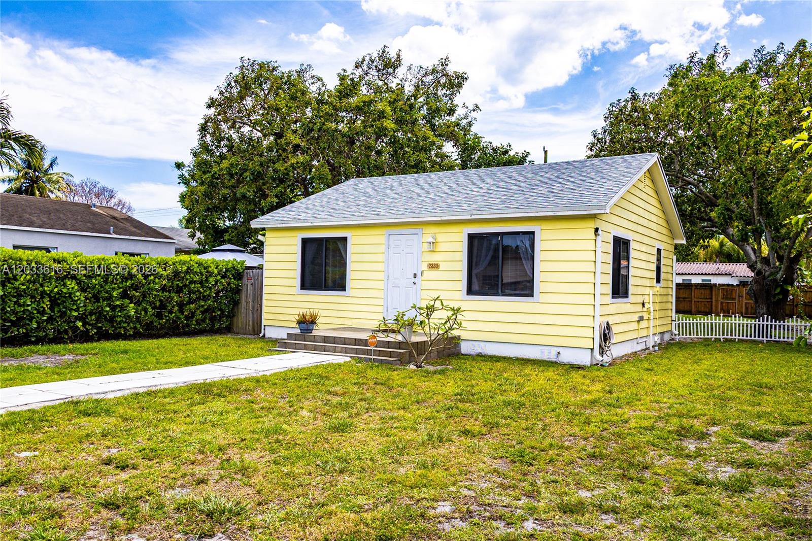 A yellow single-story house with a white door and a front lawn — 2330 Scott St, Hollywood FL 33020, HOLLYWOOD, FL