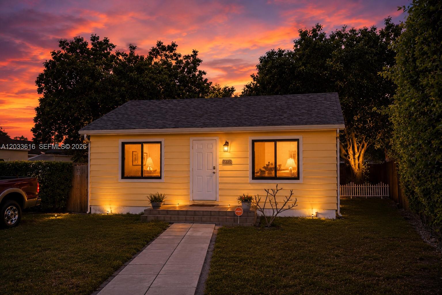 A yellow single-story house with a white door and two windows sits under a sunset — 2330 Scott St, Hollywood FL 33020, HOLLYWOOD, FL