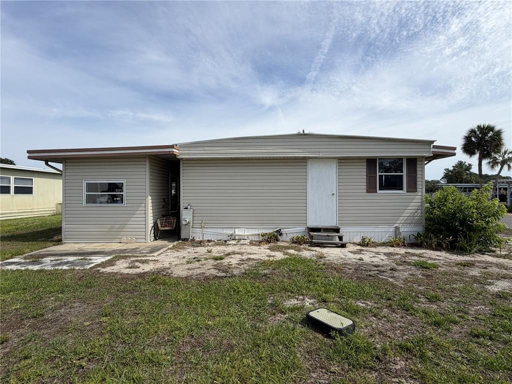 The exterior of a single-story manufactured home features beige siding, a white door, and a window — 171 PARADISE N, LEESBURG, FL