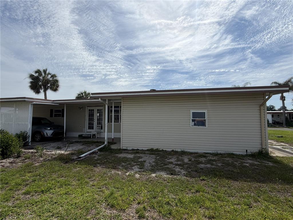 The exterior of a single-story home features light-colored siding, a carport, and a small yard — 171 PARADISE N, LEESBURG, FL
