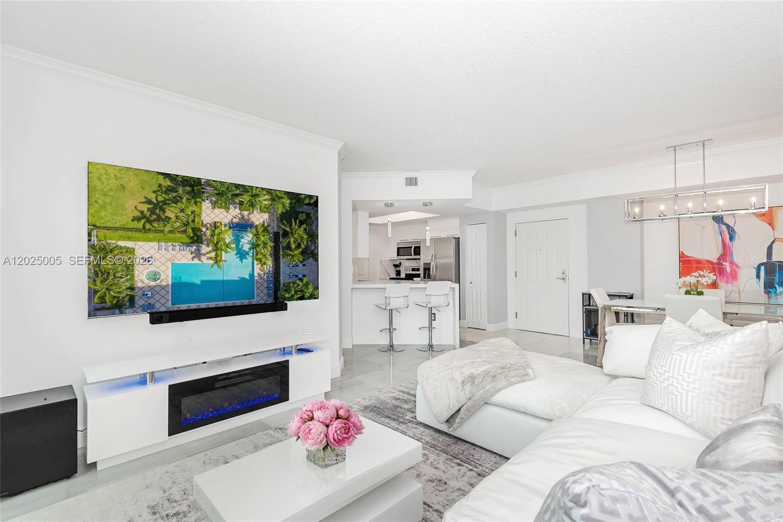 A modern living room features a white sectional sofa, a fireplace console, and an open kitchen — 2000 N Bayshore Dr # 619, Miami FL 33137, MIAMI, FL