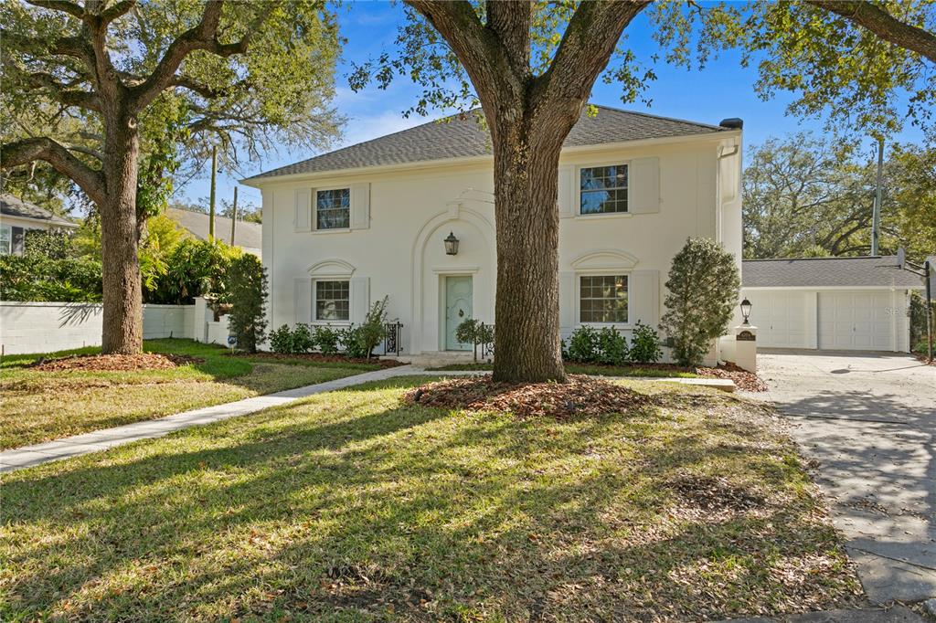 A two-story white house with a detached garage and large trees in the front yard — 4704 W BROOKWOOD DRIVE, TAMPA, FL