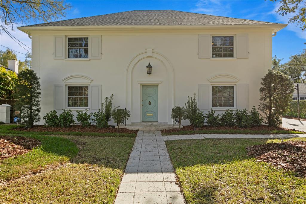 A two-story, white stucco house features a central arched entryway with a light blue door — 4704 W BROOKWOOD DRIVE, TAMPA, FL