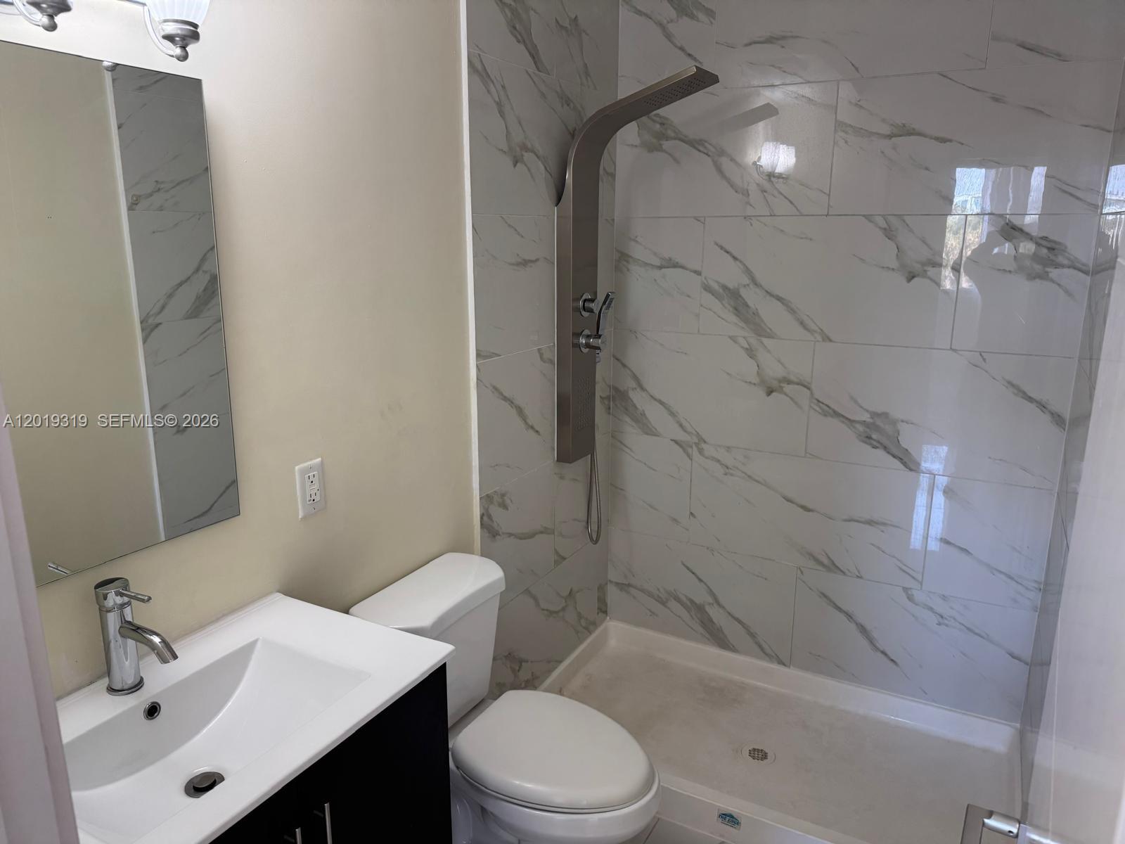 A bathroom features a vanity, toilet, and a walk-in shower with marble-look tile walls — 13724 SW 259th St, Homestead FL 33032, HOMESTEAD, FL
