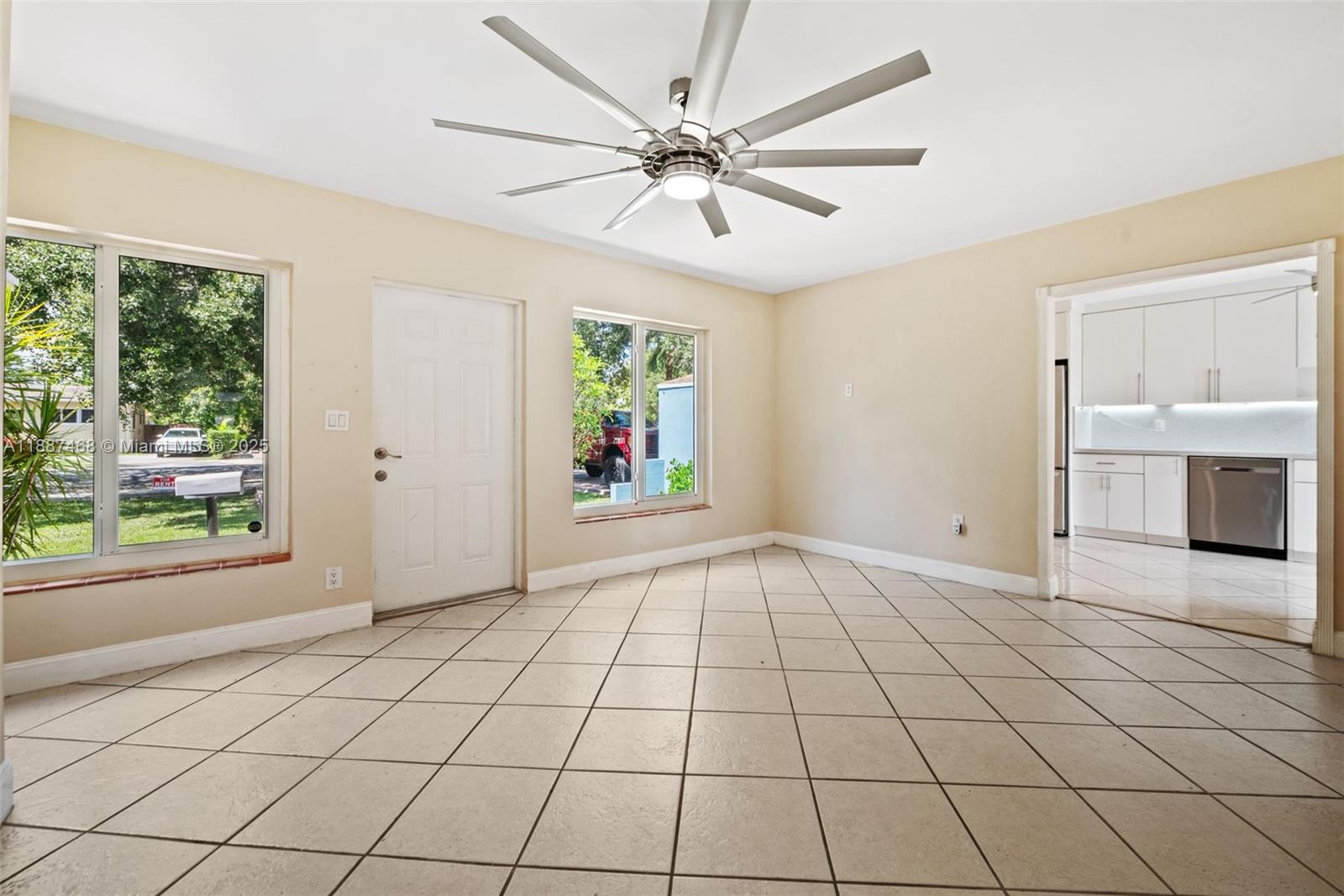 A tiled living area features a ceiling fan, two windows, and an adjacent white kitchen — 573 Palmetto Dr, Miami Springs FL 33166, MIAMI SPRINGS, FL