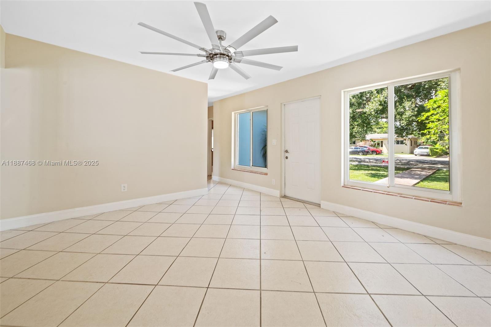 An empty room features beige walls, light-colored tile flooring, a ceiling fan, and two windows — 573 Palmetto Dr, Miami Springs FL 33166, MIAMI SPRINGS, FL