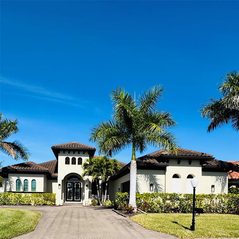 A single-story house with a tile roof, arched windows, and palm trees in the yard — 8533 S LAKE CIRCLE, FORT MYERS, FL