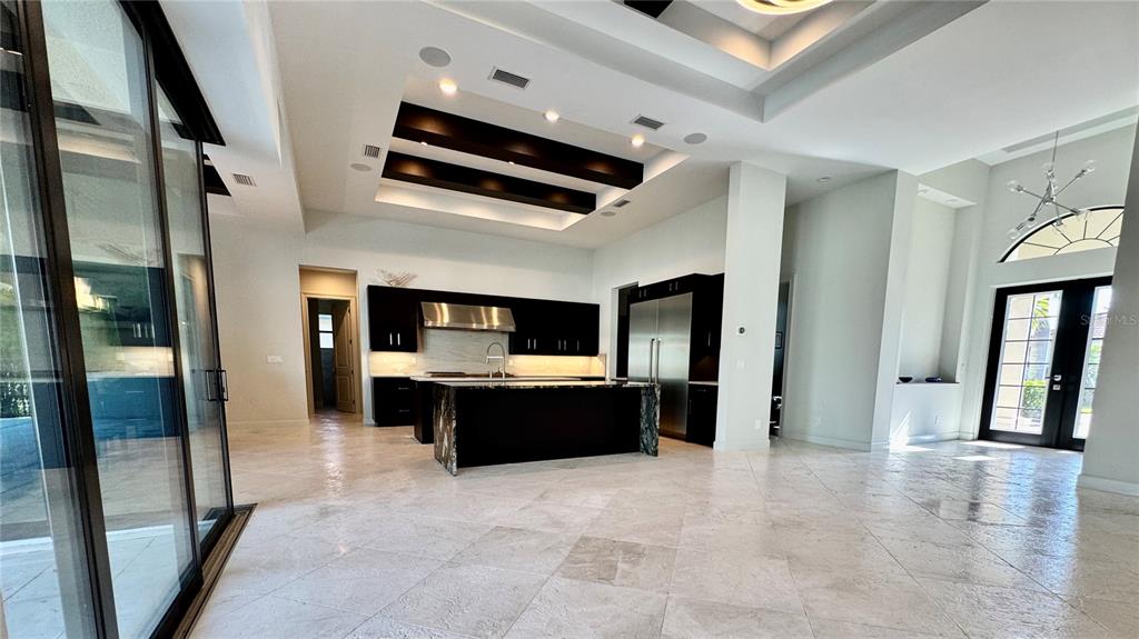 A modern kitchen features dark cabinetry, a large island, and a tray ceiling with beams — 8533 S LAKE CIRCLE, FORT MYERS, FL