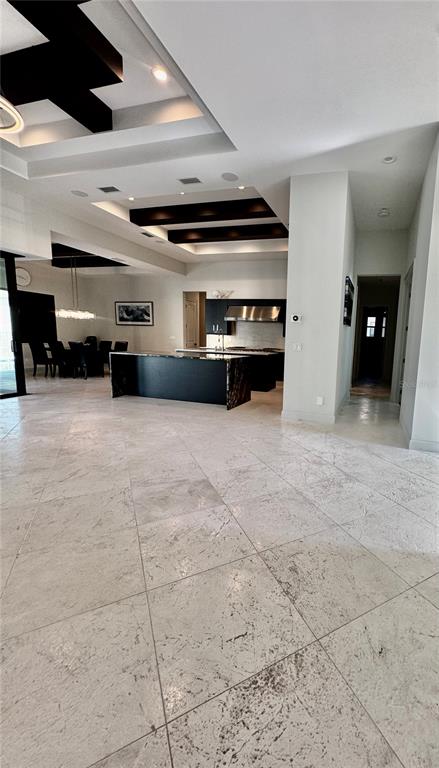 A spacious open-concept kitchen and dining area features dark cabinetry, tray ceilings, and tile flooring — 8533 S LAKE CIRCLE, FORT MYERS, FL