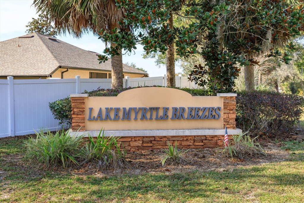 A stone and stucco monument sign for Lake Myrtle Breezes stands in a grassy yard — 1002 MYRTLE BREEZES COURT, FRUITLAND PARK, FL