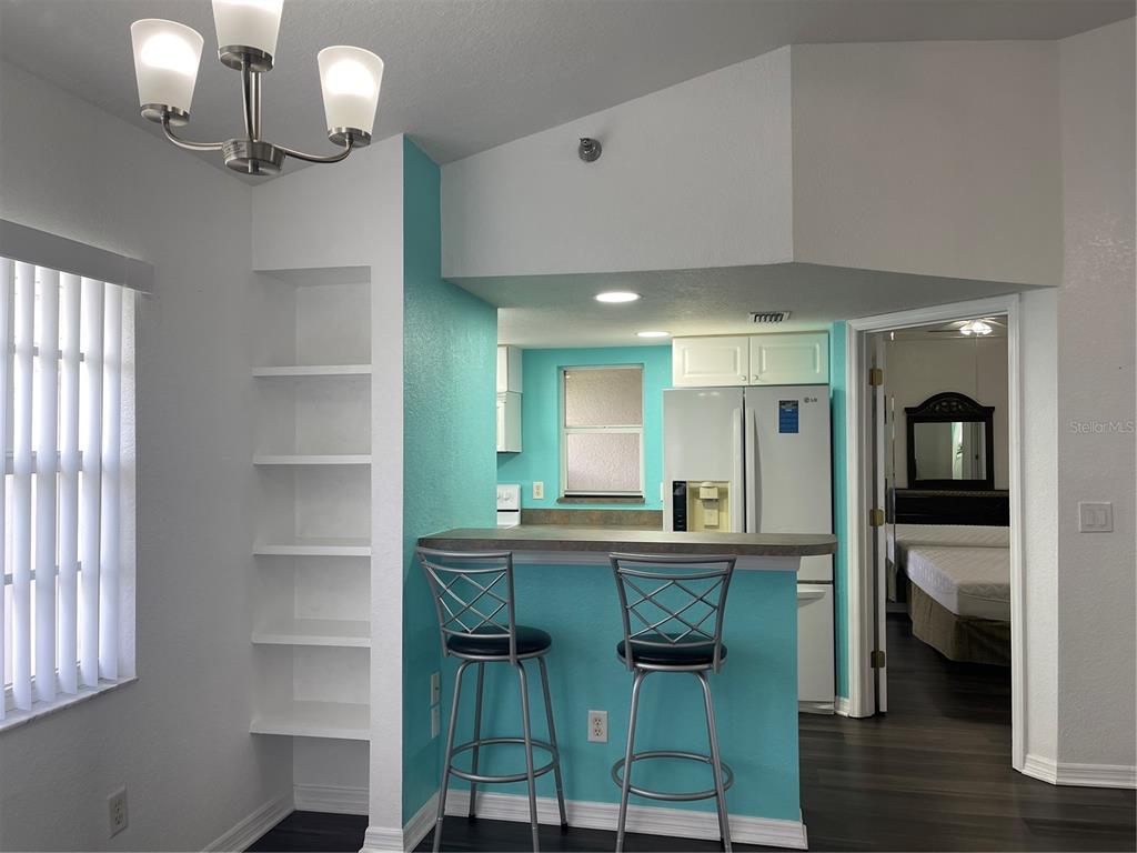 A kitchen with a breakfast bar, teal walls, and built-in shelving opens to a bedroom — 21146 FOUNTAIN VIEW LANE UNIT 4303, LUTZ, FL