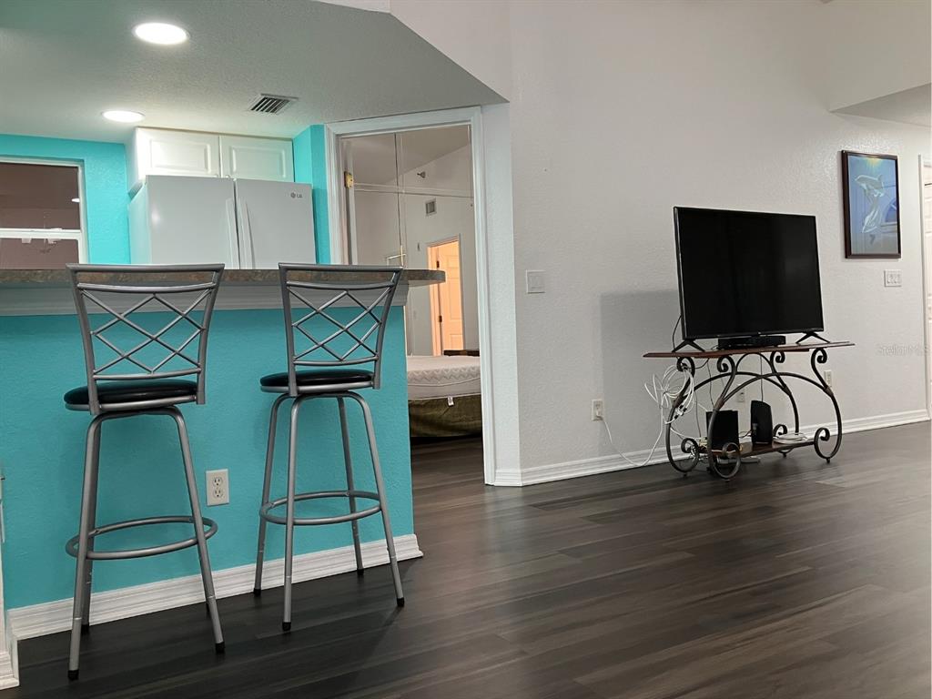 A kitchen island with two bar stools sits in front of a living area — 21146 FOUNTAIN VIEW LANE UNIT 4303, LUTZ, FL