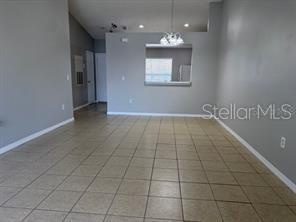 A living area with light gray walls, tile flooring, and a pass-through window to the kitchen — 13403 FAIRWAY GLEN DRIVE UNIT 204, ORLANDO, FL