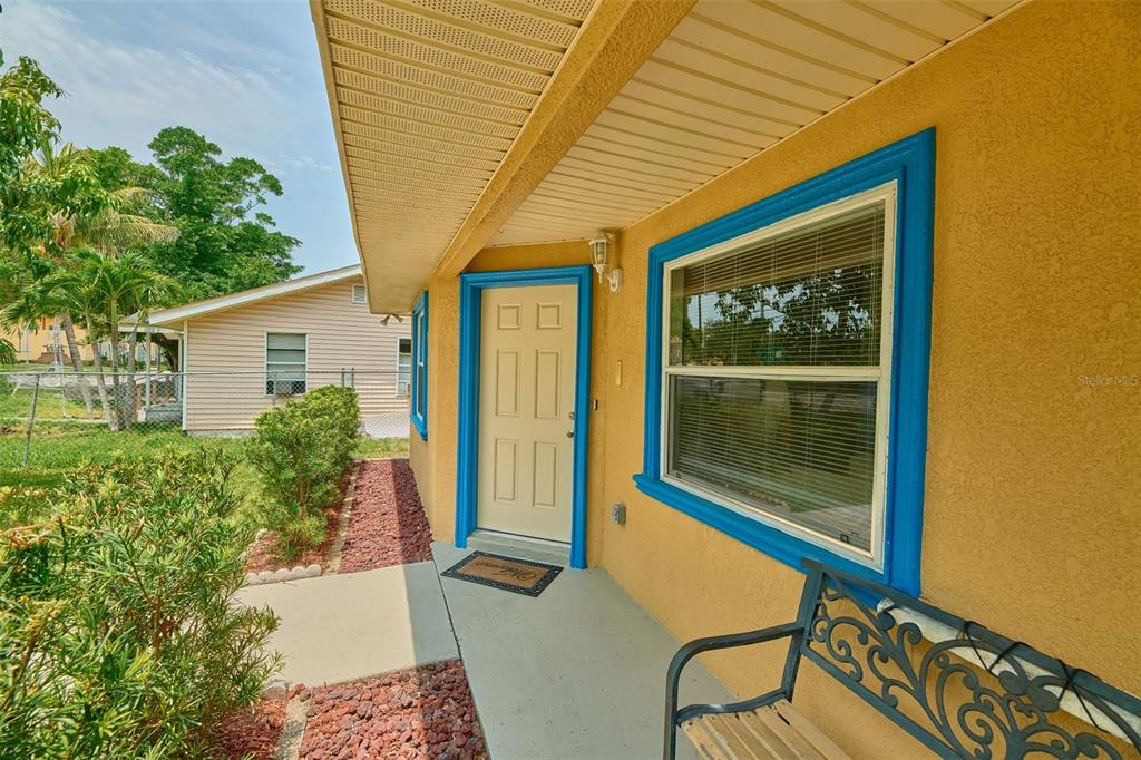 A yellow house exterior features a front door and window with bright blue trim — 212 13TH AVENUE W, BRADENTON, FL