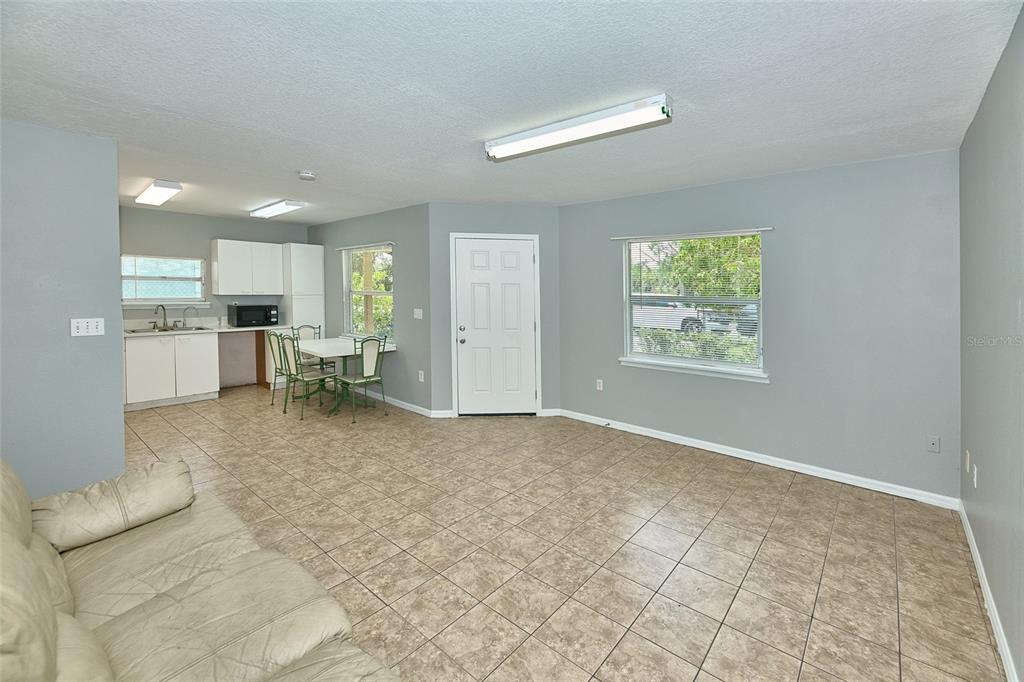 An open-concept living and dining area features light gray walls, tile flooring, and white cabinetry — 212 13TH AVENUE W, BRADENTON, FL