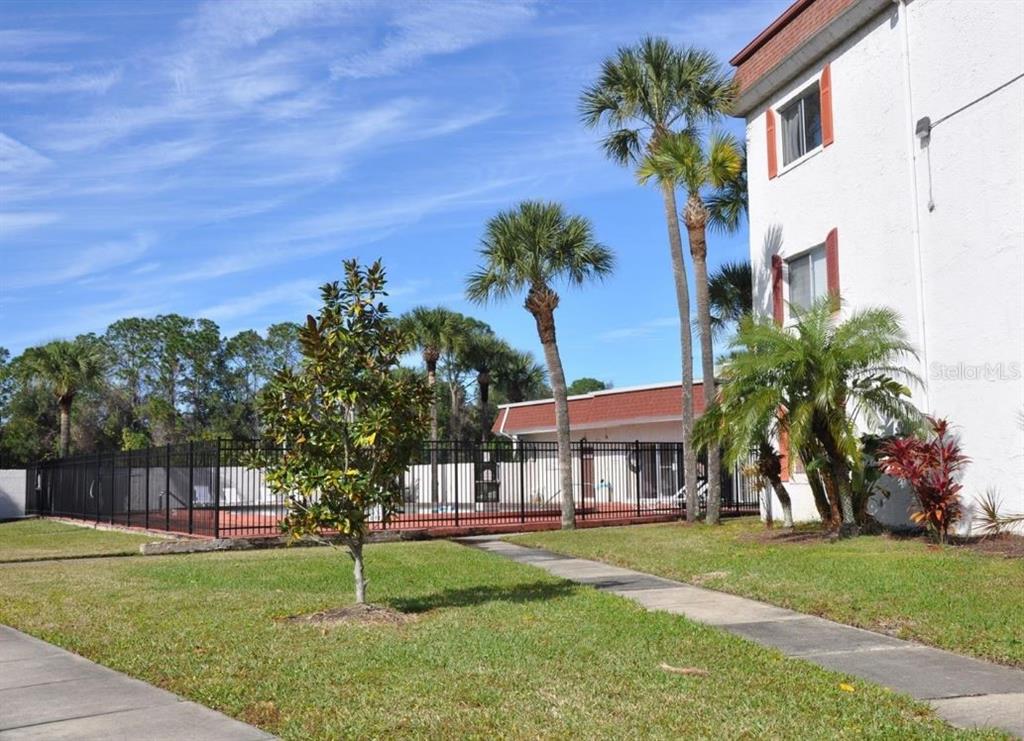 An outdoor view of a fenced swimming pool area next to a multi-story apartment building — 4575 S TEXAS AVENUE UNIT 307, ORLANDO, FL