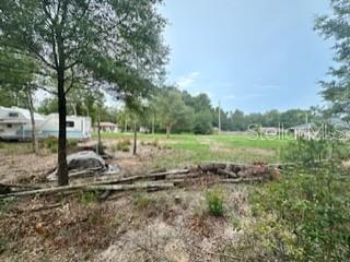 A grassy, partially cleared lot features a parked recreational vehicle and scattered fallen tree branches — NW 56TH COURT, OCALA, FL