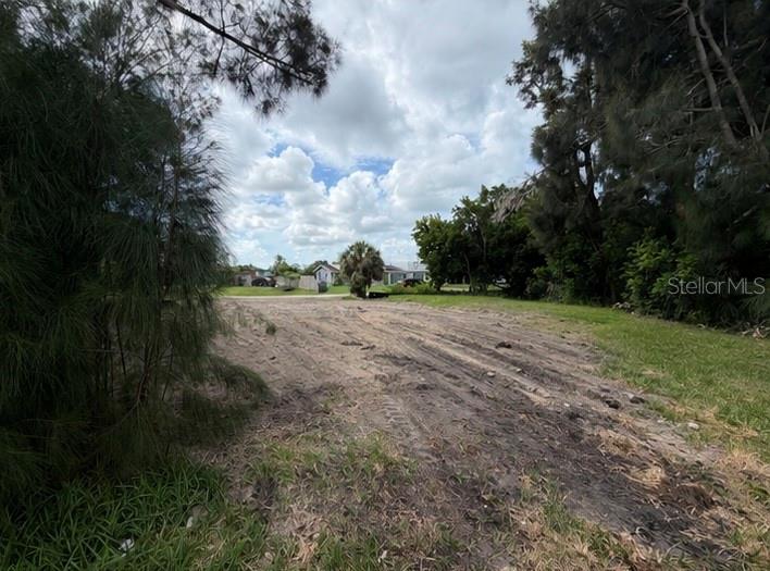 A vacant, cleared dirt lot is framed by trees under a cloudy sky — 1020 LINDEN ROAD, VENICE, FL