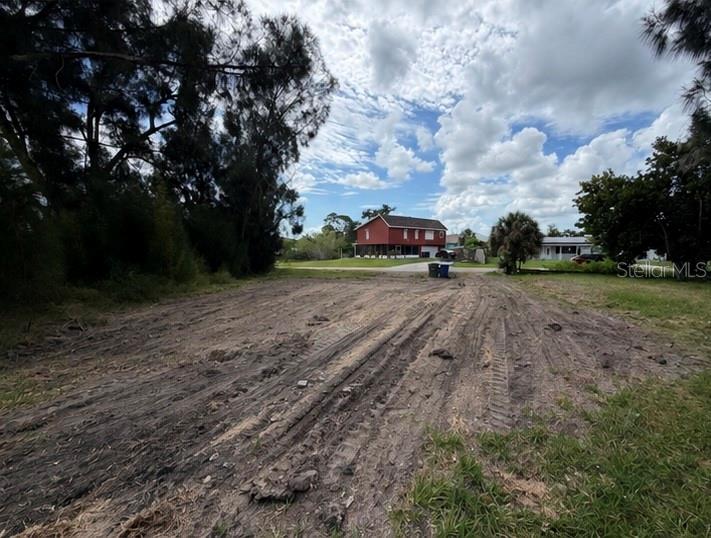 A cleared, dirt-covered vacant lot with tire tracks sits in front of a red house — 1020 LINDEN ROAD, VENICE, FL