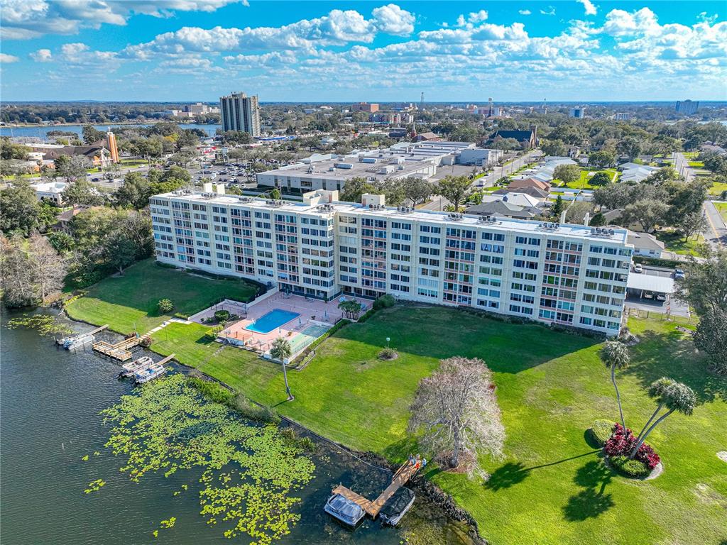 An aerial view of a multi-story apartment building with a pool and lakefront dock — 700 MIRROR TERRACE NW UNIT 705, WINTER HAVEN, FL