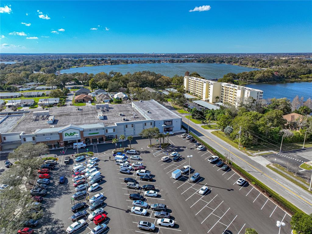 An aerial view shows a Publix grocery store, a parking lot, and a nearby lake — 700 MIRROR TERRACE NW UNIT 705, WINTER HAVEN, FL