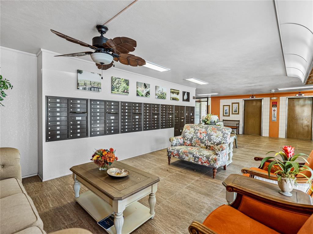 A lobby area features a wall of mailboxes, a floral sofa, and a coffee table — 700 MIRROR TERRACE NW UNIT 705, WINTER HAVEN, FL