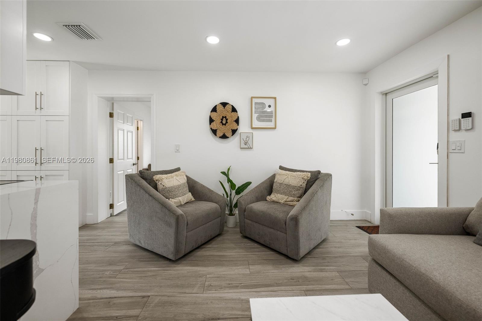 A living area features two gray armchairs, a small plant, and wall art — 1448 NE 25th Ct, Pompano Beach FL 33064, POMPANO BEACH, FL
