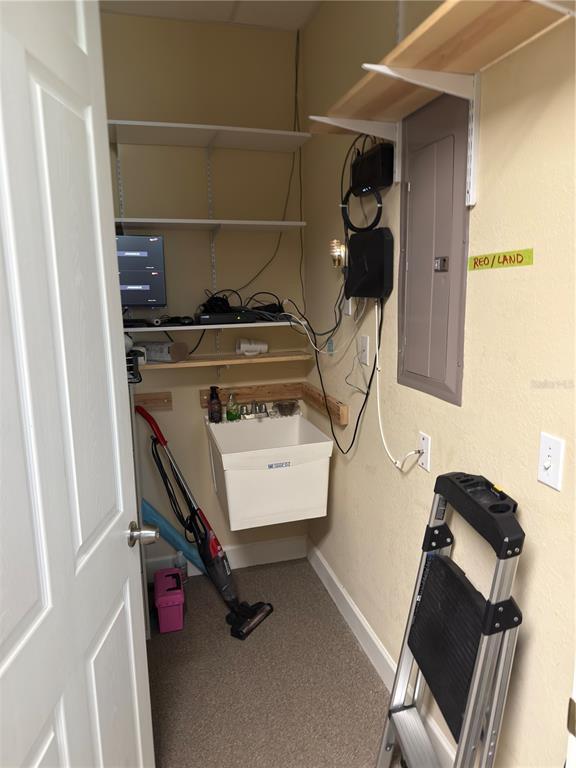 A utility closet features a wall-mounted sink, storage shelving, electronic equipment, and a step ladder — 2563 N TOLEDO BLADE BOULEVARD UNIT 2, NORTH PORT, FL