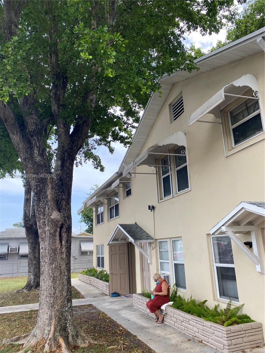 A two-story stucco apartment building features metal window awnings and a brick planter box — 26 SE 13th Ter # 7, Dania Beach FL 33004, DANIA BEACH, FL